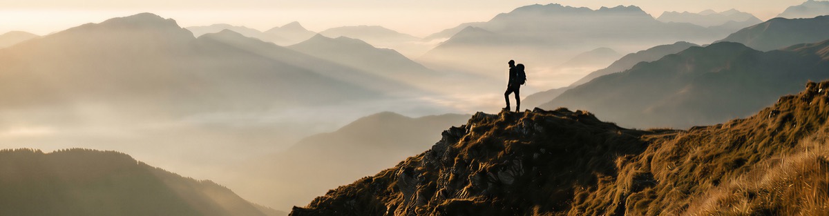 A hiker on a ridge above a misty valley